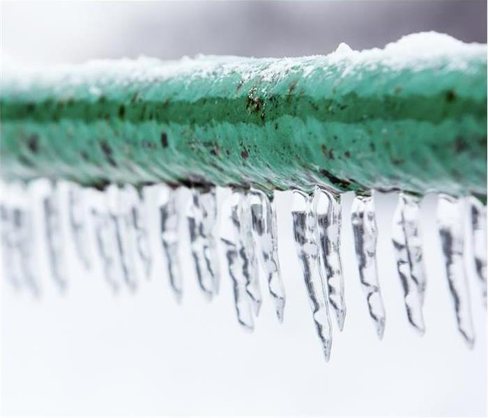 A frozen pipe with icicles hanging from it.